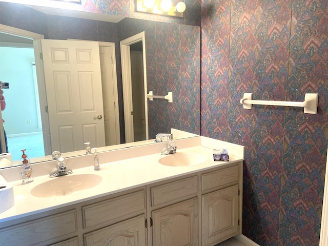 full bath featuring double vanity, a sink, and wallpapered walls