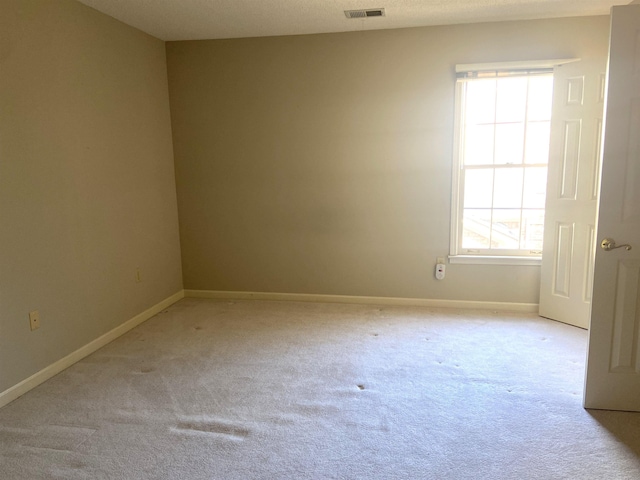 unfurnished room with light colored carpet, visible vents, and baseboards