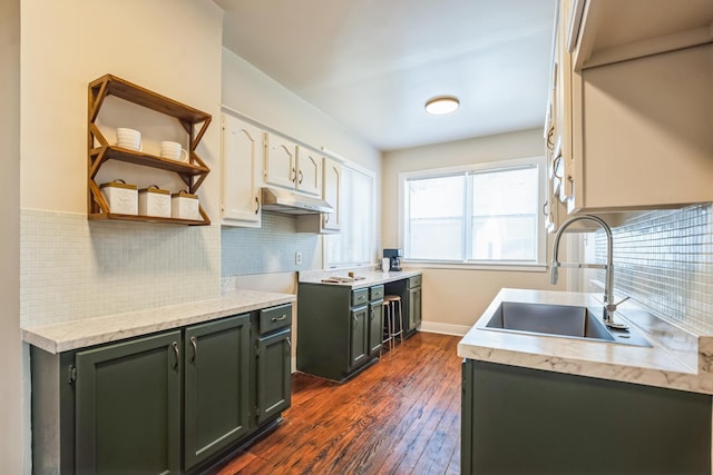 kitchen featuring dark wood-style floors, light countertops, under cabinet range hood, open shelves, and a sink