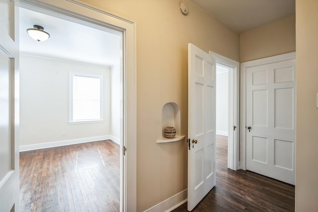 corridor featuring dark wood-style flooring and baseboards