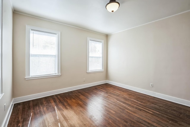 empty room featuring ornamental molding, dark wood finished floors, and baseboards