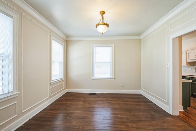 empty room featuring baseboards, visible vents, dark wood-style floors, ornamental molding, and a decorative wall