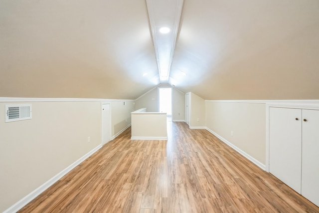 bonus room featuring lofted ceiling with beams, light wood-style floors, baseboards, and visible vents