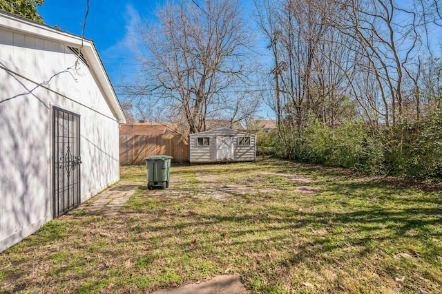 view of yard featuring an outbuilding, a storage unit, and fence