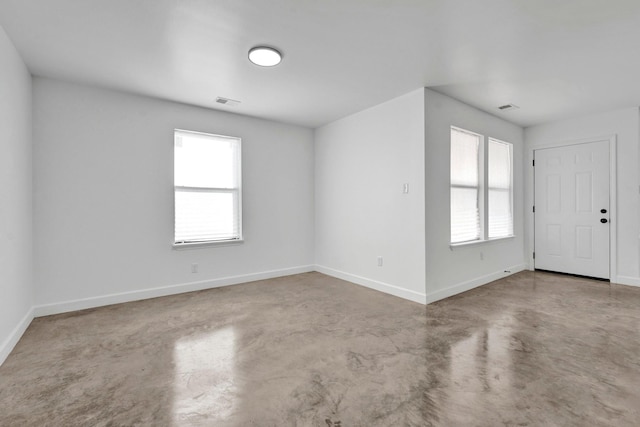 empty room featuring baseboards, concrete floors, and a healthy amount of sunlight