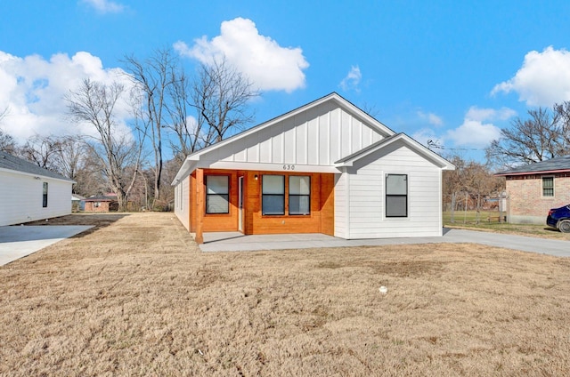 back of house featuring a porch, board and batten siding, and a yard