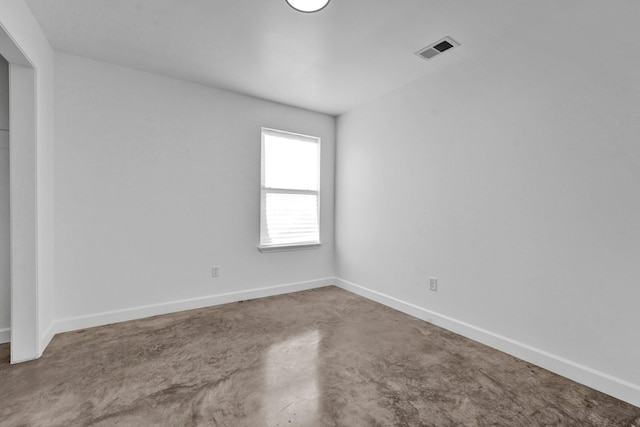 spare room featuring baseboards, concrete floors, and visible vents