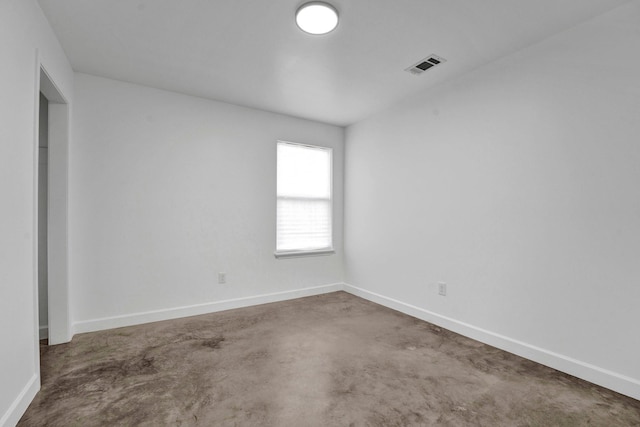 spare room with concrete flooring, visible vents, and baseboards