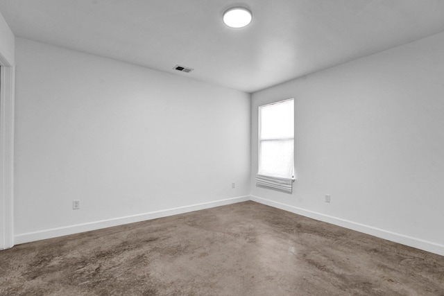 empty room featuring concrete floors, visible vents, and baseboards