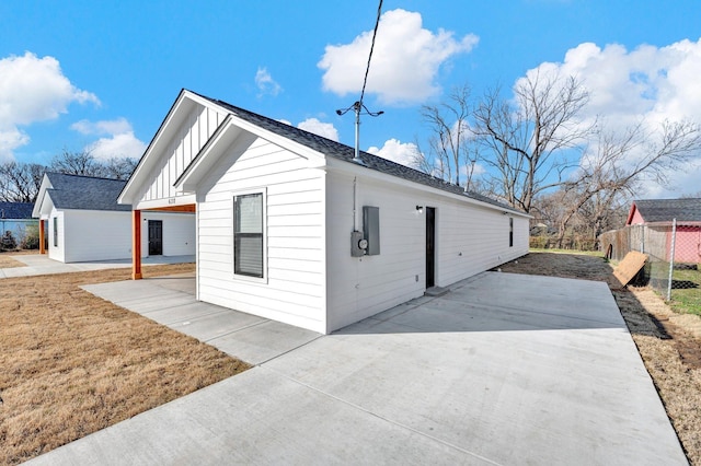 view of property exterior with a patio, board and batten siding, and fence