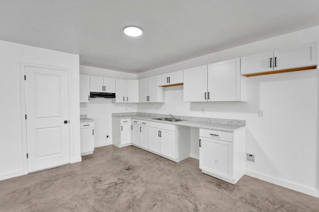 kitchen featuring light countertops, white cabinetry, a sink, concrete floors, and baseboards