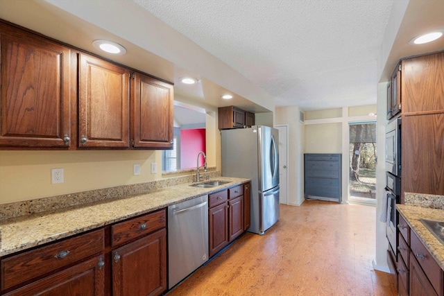 kitchen featuring light stone counters, recessed lighting, appliances with stainless steel finishes, a sink, and a textured ceiling