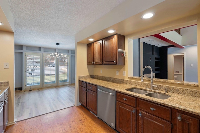 kitchen featuring stainless steel dishwasher, light wood-style floors, a sink, a textured ceiling, and light stone countertops