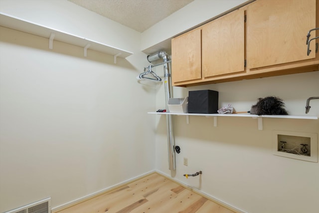 clothes washing area featuring hookup for a washing machine, hookup for a gas dryer, cabinet space, visible vents, and light wood-style floors