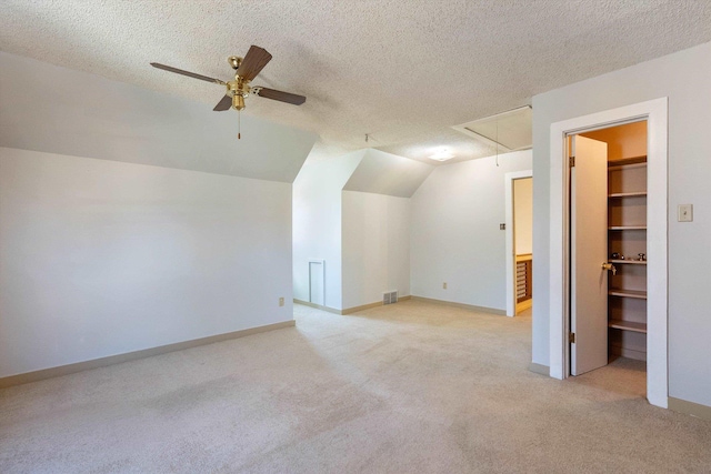 bonus room featuring a textured ceiling, visible vents, attic access, and light colored carpet