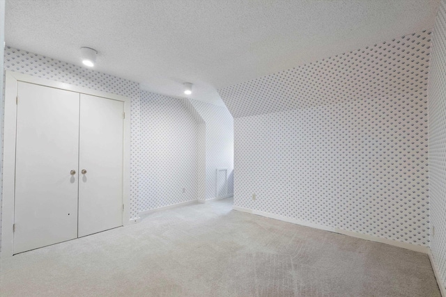 bonus room with a textured ceiling, baseboards, carpet flooring, and wallpapered walls