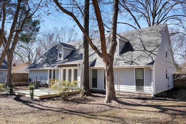 view of front of house with roof with shingles, fence, and a wooden deck