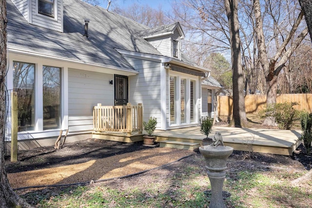 back of property featuring roof with shingles, fence, and a wooden deck