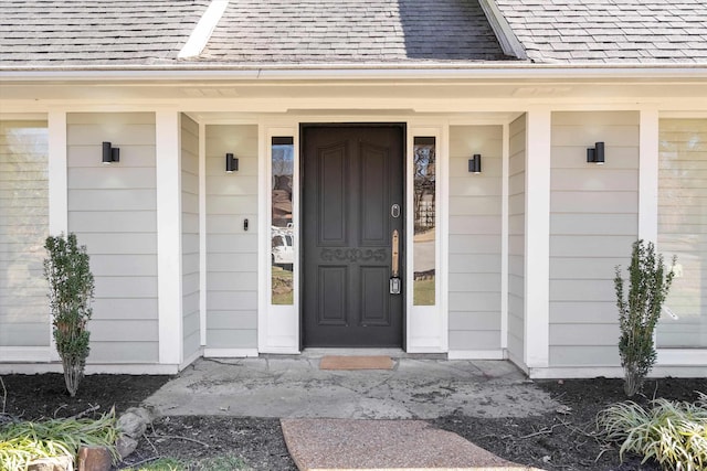 doorway to property featuring roof with shingles