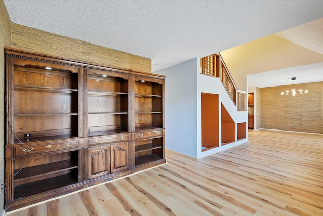 interior space featuring light wood finished floors, stairway, a chandelier, and a textured ceiling