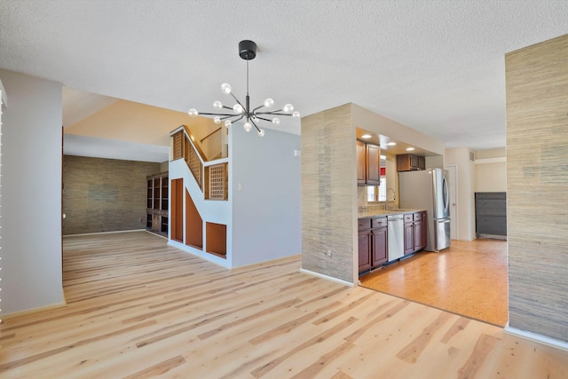 kitchen featuring appliances with stainless steel finishes, light countertops, a textured ceiling, light wood-type flooring, and a notable chandelier