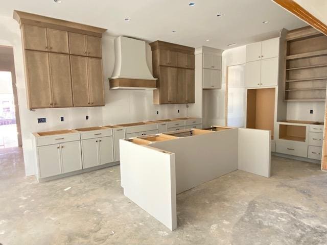 kitchen featuring a center island, custom range hood, open shelves, and unfinished concrete floors