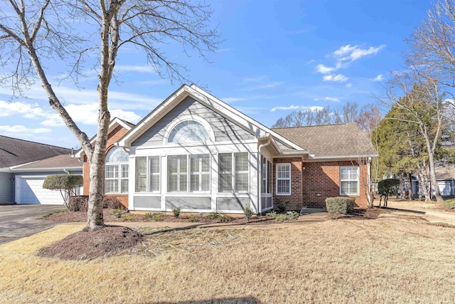 single story home featuring a garage, a front yard, brick siding, and driveway