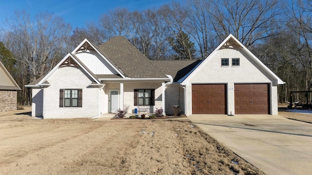 view of front of home featuring a garage, a shingled roof, concrete driveway, covered porch, and brick siding