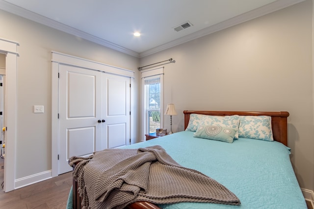 bedroom with baseboards, visible vents, dark wood-type flooring, crown molding, and a closet