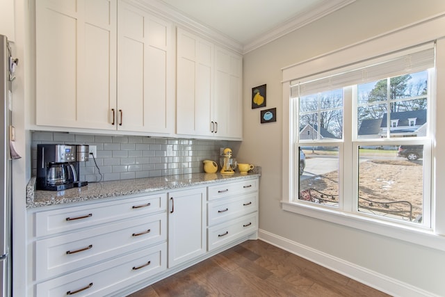 kitchen with ornamental molding, backsplash, white cabinetry, and light stone countertops