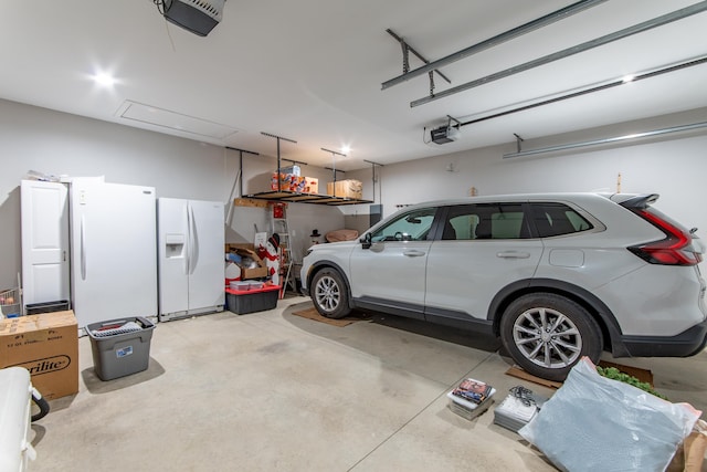 garage with a garage door opener, freestanding refrigerator, and white refrigerator with ice dispenser