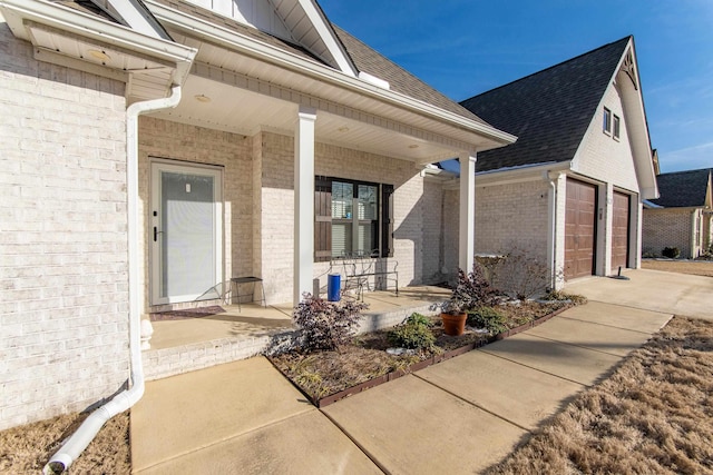 entrance to property with a porch, brick siding, a shingled roof, and a garage