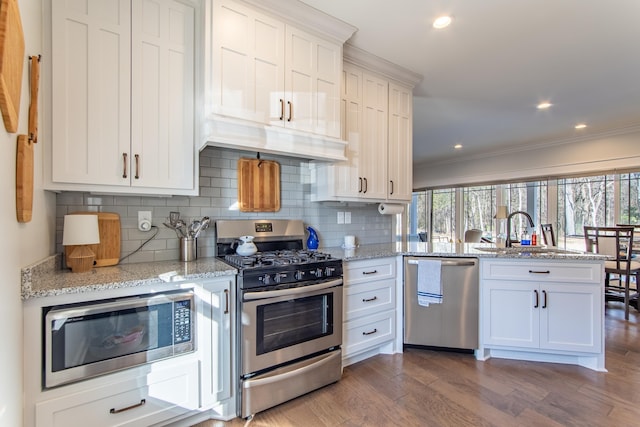 kitchen featuring appliances with stainless steel finishes, a healthy amount of sunlight, white cabinetry, and dark wood-style floors