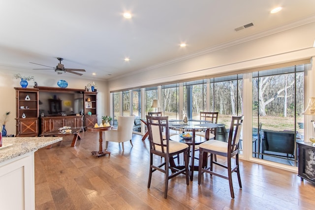 dining area featuring light wood-style floors, a healthy amount of sunlight, visible vents, and crown molding