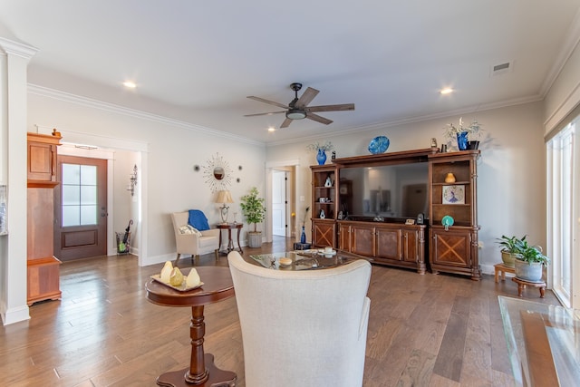 living room with ornamental molding, wood finished floors, visible vents, and baseboards