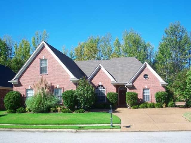 traditional-style house with driveway, brick siding, and a front yard