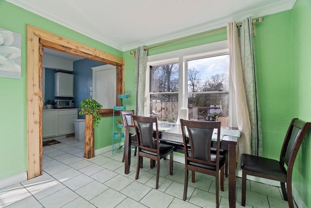 dining space with light tile patterned floors, baseboards, and crown molding