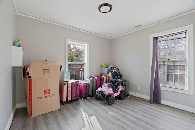 recreation room with baseboards, visible vents, crown molding, and light wood finished floors