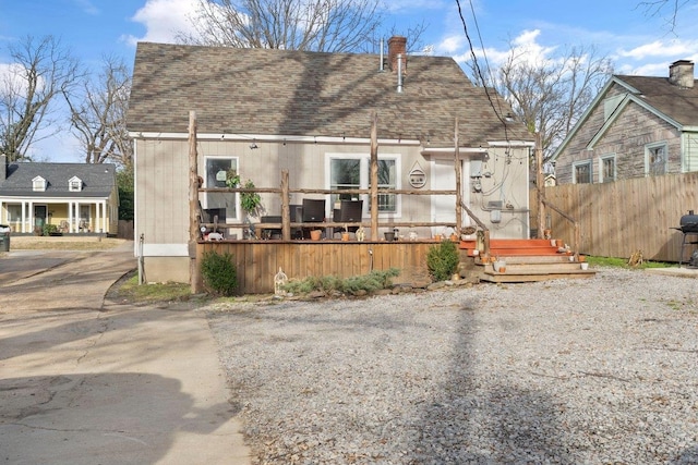 view of front of home featuring fence and roof with shingles