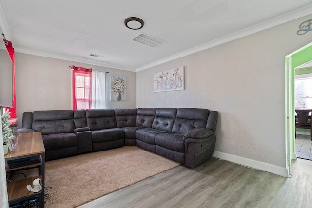 living area featuring baseboards, wood finished floors, visible vents, and crown molding