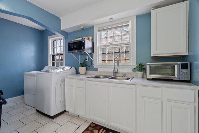 laundry area with cabinet space, plenty of natural light, washer and dryer, and a sink