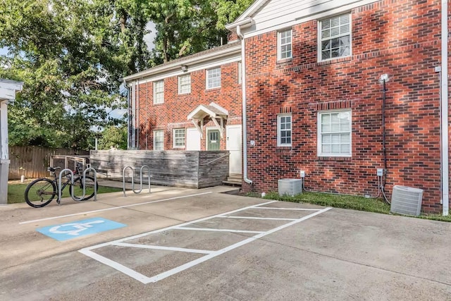 exterior space featuring brick siding, fence, and central air condition unit