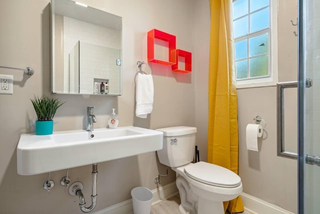 full bathroom with a sink, walk in shower, toilet, and baseboards