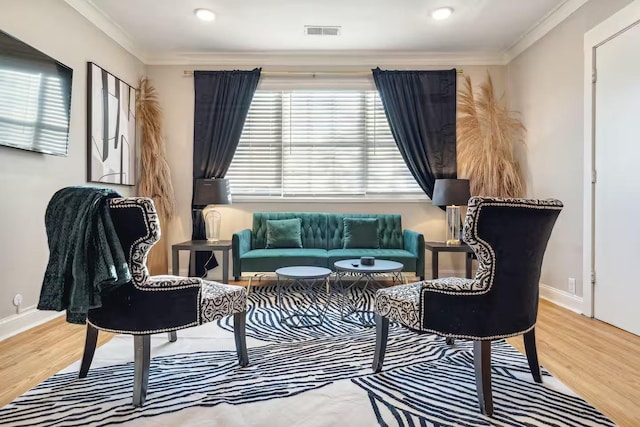 sitting room featuring baseboards, visible vents, ornamental molding, and wood finished floors