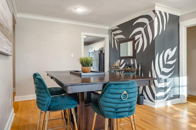 dining area with baseboards, ornamental molding, and wood finished floors