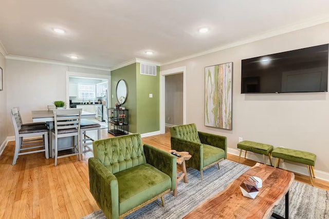 living room with ornamental molding, light wood-type flooring, and baseboards