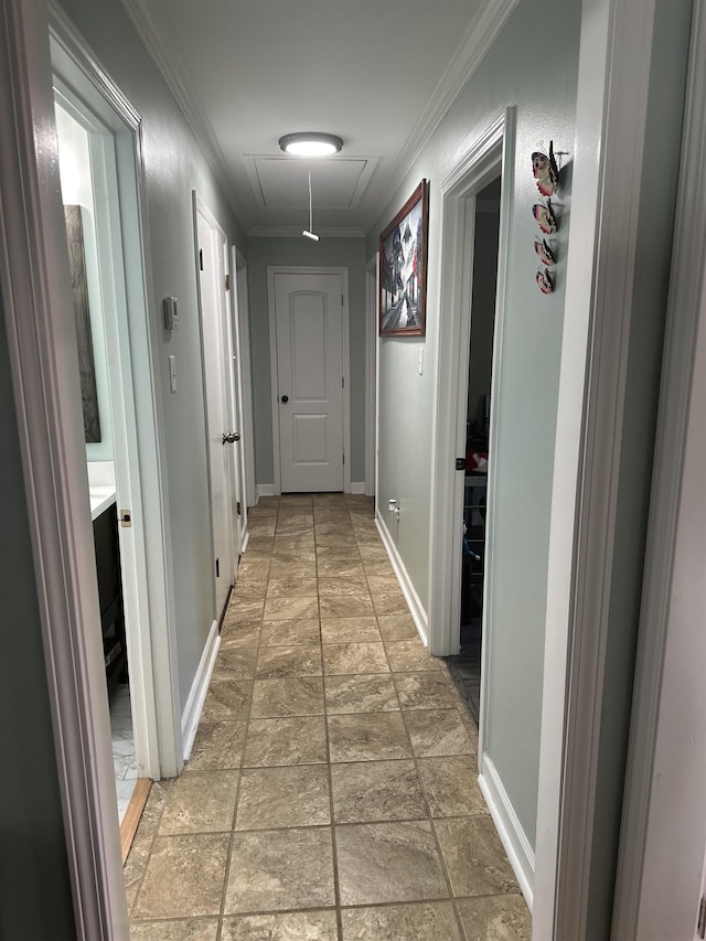 hall featuring baseboards, stone finish flooring, attic access, and crown molding