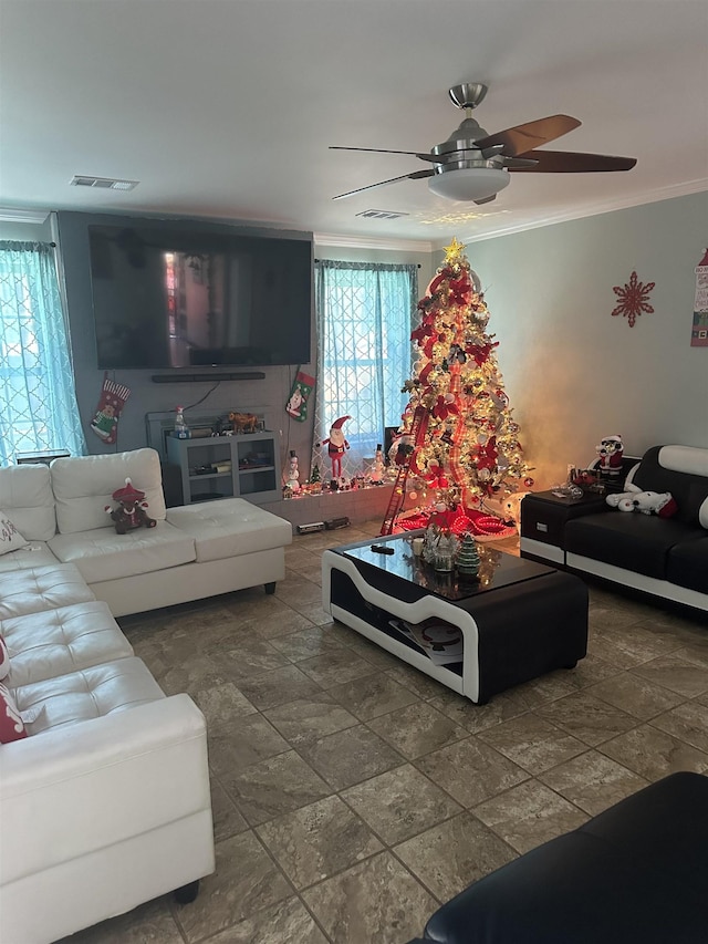 living room with stone finish flooring, ornamental molding, visible vents, and a ceiling fan