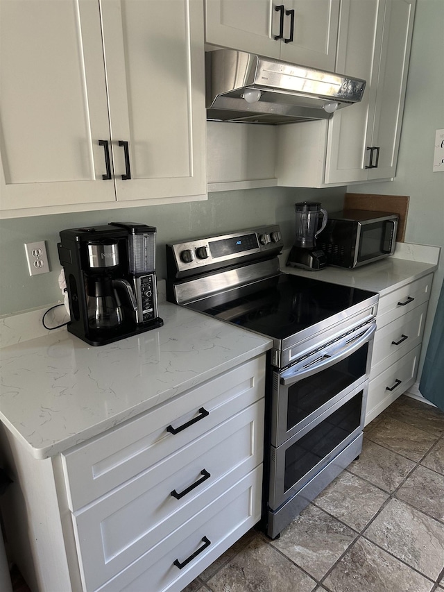 kitchen featuring black microwave, range with two ovens, under cabinet range hood, white cabinets, and light stone countertops