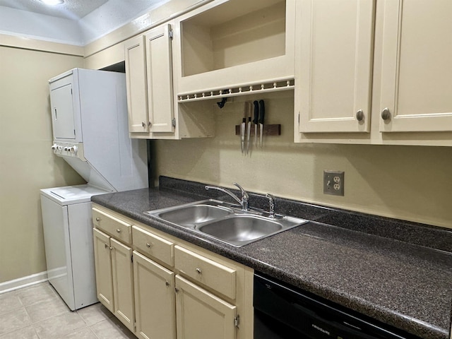 kitchen featuring black dishwasher, dark countertops, a sink, and stacked washer and clothes dryer